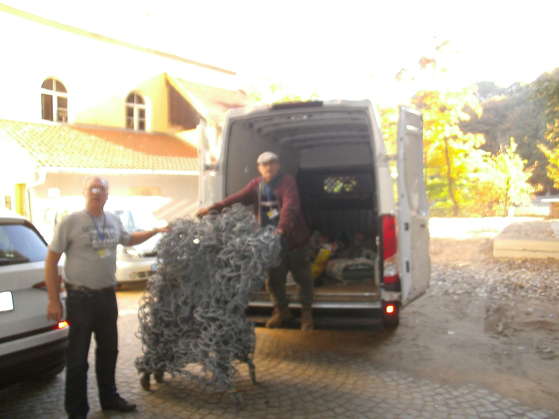 Zwei Männer schieben eine große Metallskulptur auf Rollen in einen Transporter.